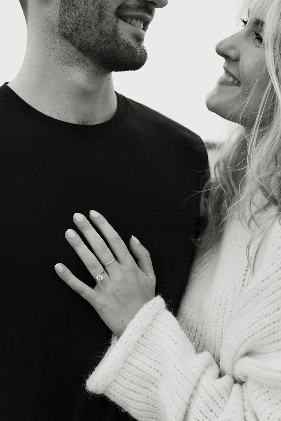 Black-and-white close-up of Kaitlyn resting her hand, and her engagement ring, on Jack