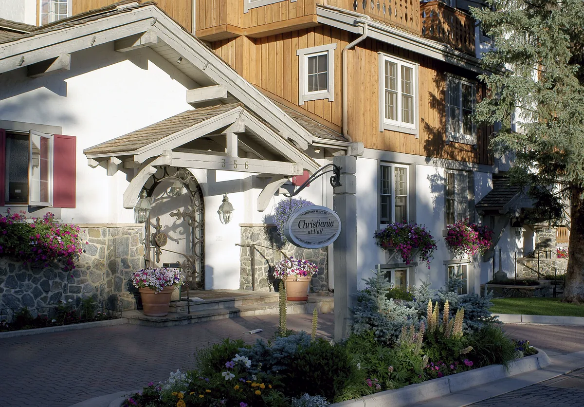 An alpine-style lodge in Vail Village with window boxes and flower beds in summer